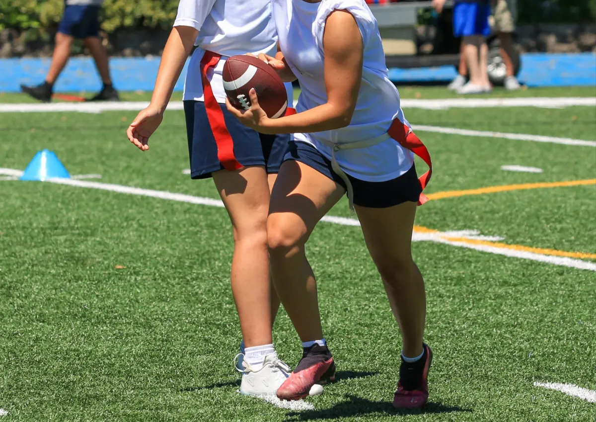 equipamiento para jugar tocho bandera: jugadoras con cinturón de banderas rojas y balón durante un handoff